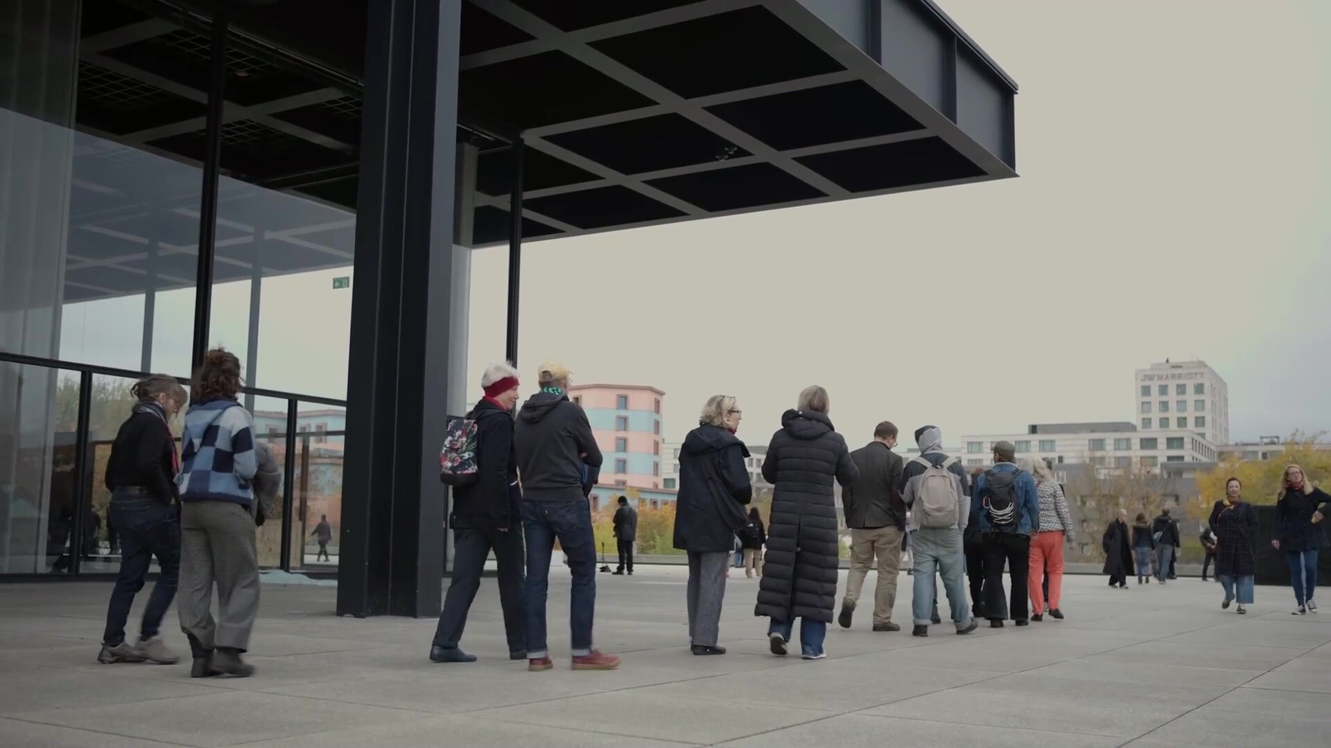 Visitors walking together past the black steel pavilion of the Neue Nationalgalerie, Berlin