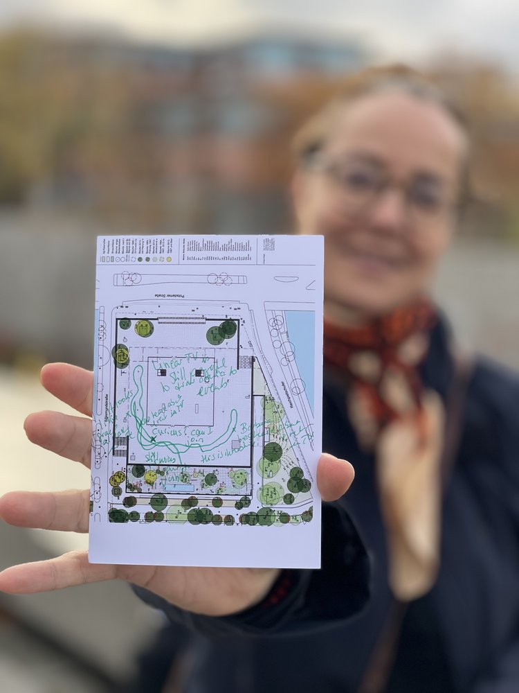 A visitor holding up their filled-out postcard from Walking With Our Future Ideas